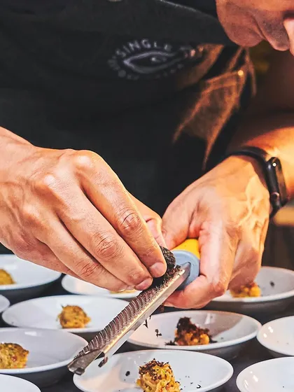The final touch is everything. Here, I'm shaving fresh black truffle over a dish, adding that last layer of aroma and luxury that defines my culinary approach. It's these details that make an event unforgettable.