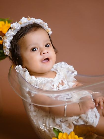 This baby girl looks so sweet and curious sitting in a clear bathtub prop, surrounded by sunflowers.