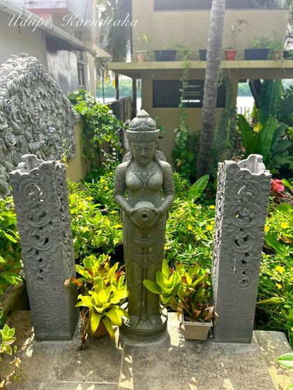 A beautiful garden setup in Udupi, Karnataka. Our client has created a stunning focal point with a traditional Balinese statue flanked by two intricately carved stone pillars.