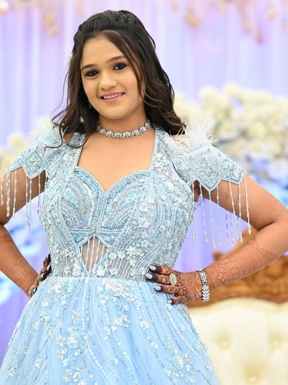 A full-length portrait of a happy guest, confidently showing off her party mehendi.