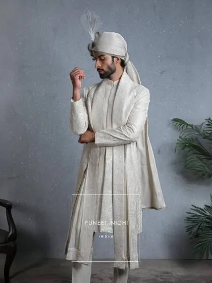 In the purity of ivory lies the soul of tradition. This sherwani, with its intricate motifs and feather-touched turban, is more than fabric; it is craftsmanship woven into legacy.