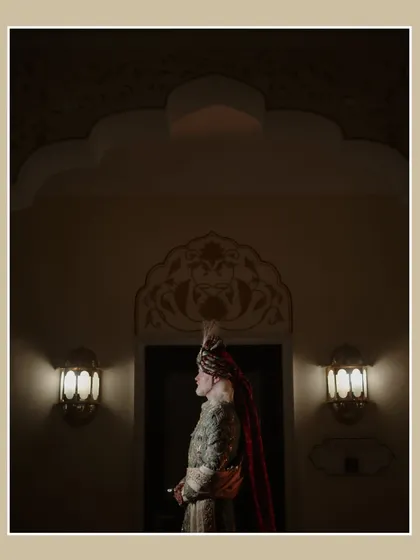 A dramatic portrait of the groom at his Jaipur wedding. The low-light and architectural details create a moody and regal image, highlighting his traditional attire.