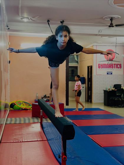 Another angle of the balance beam routine, showing the student maintaining her balance with arms outstretched. Each pose is practiced until it is flawless.