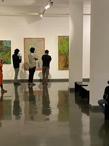 A view of the gallery with visitors observing the large canvases.