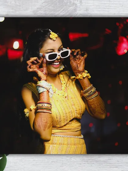 The fun and playful side of the bride during her Haldi. Her cool sunglasses and confident pose show off her personality amidst the traditional celebration.