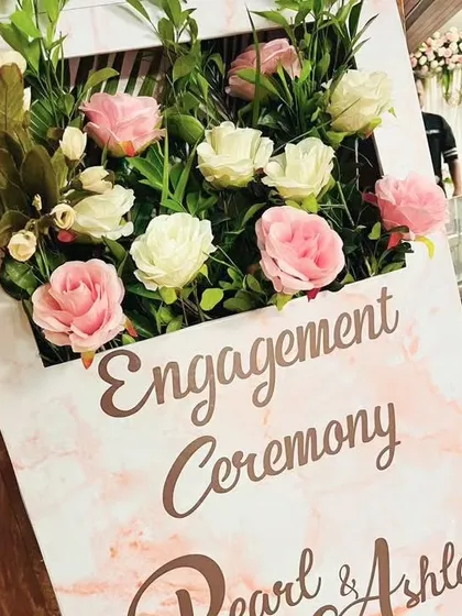 A close-up of a modern and elegant welcome sign for Pearl and Ashley's engagement ceremony. The pink marble texture is complemented by a 3D floral arrangement, creating a chic and stylish first impression.