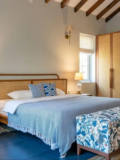 This bedroom in a Goan villa balances rustic charm with refined design. We crafted a custom bed with a natural rattan headboard and a matching wardrobe, bringing texture and warmth to the space. The design reflects the home's personality, creating a layered and textured escape.