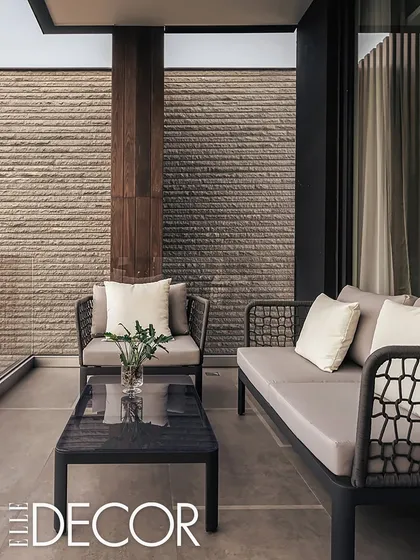 Our Carbonado residence, featured in Elle Decor India, was inspired by the rare Black Diamond. The design is serene and minimal, with a focus on comfort, calmness, and a strong connection to nature, seen here in the textured stone wall and simple outdoor seating.