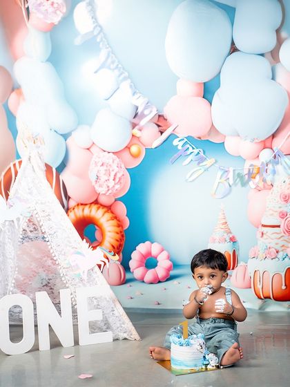 The cake smash is underway! This candid shot captures the messy fun of a first birthday, a moment of pure, uninhibited joy that families will treasure forever.