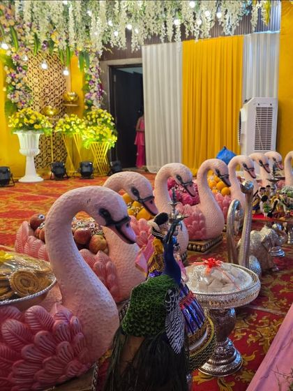 A close-up of a swan-themed offering table, with pink swan-shaped bowls holding fruits and sweets.