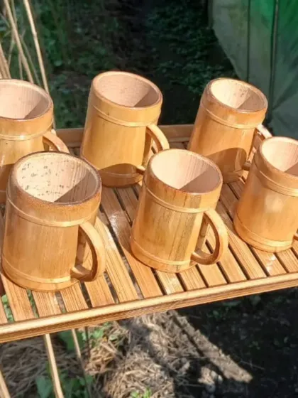A handcrafted bamboo serving set, featuring a slatted tray and six matching bamboo mugs. This set, inspired by the crafts of Northeast India, is perfect for serving tea or other beverages with a touch of natural, rustic elegance.