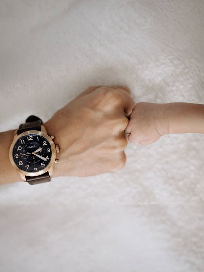 A tiny fist bump between father and baby. This photo captures a sweet and modern take on the bond between a parent and their child.