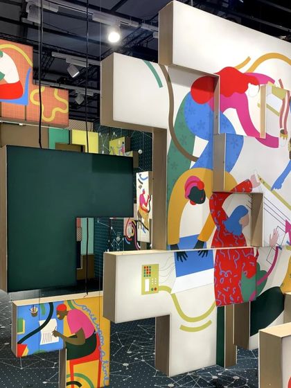 A detail of the 'Solo Commerce' installation, where colorful illustrations on floating blocks create a vibrant, layered effect. The artwork depicts the various activities and freedoms of the modern gig worker.