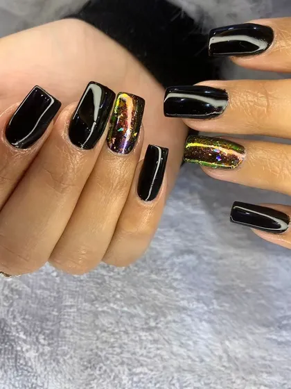 A close-up of the multi-chrome cat eye accent nail against the glossy black polish.