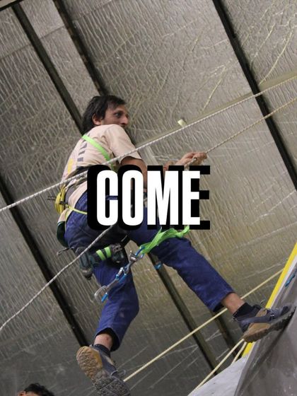 Come and climb. A setter rappels down after completing a section of the wall. We're getting everything ready for an exhilarating competition full of fun and excitement.