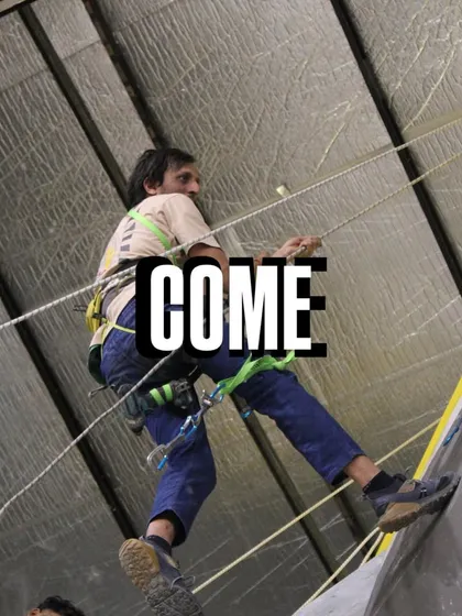 Come and climb. A setter rappels down after completing a section of the wall. We're getting everything ready for an exhilarating competition full of fun and excitement.