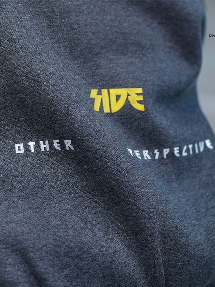 Detail shot of the 'Other Perspective' text on the hood, a subtle design element that adds character to the piece.