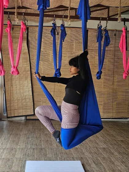 A seated side stretch using the aerial silk for support. This allows for a deeper stretch along the side of the body, improving flexibility in the spine and shoulders.