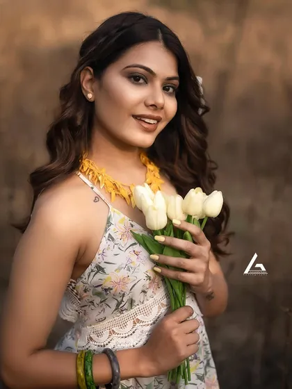 Adding a simple prop like a bouquet of flowers can enhance the story of a portrait. This close-up shot has a soft, romantic feel, highlighting the model's expression and the delicate details of the flowers and her jewelry.