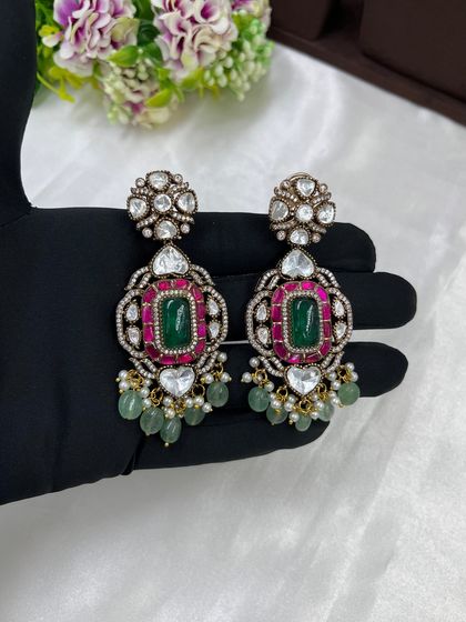 A heavy bridal choker with a unique heart-shaped Kundan setting. The piece is centered with an emerald and ruby stone, complemented by hanging pearls and mint-green beads.