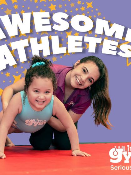 This image shows the direct, encouraging coaching that helps children thrive. The instructor's smile reflects the positive and nurturing atmosphere of the gym.