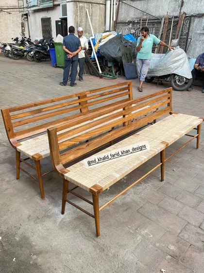 Two handcrafted benches with woven seating and a slatted backrest, ready for delivery. These versatile pieces can be used for dining seating, in an entryway, or on a covered patio, and are built from durable teak wood.