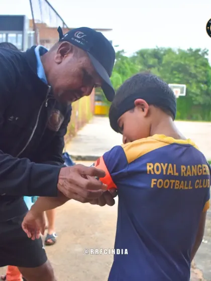 More than just a coach. Here, our head coach helps a young player with his captain's armband before a match. We believe in building leaders on and off the pitch through personal guidance and mentorship.