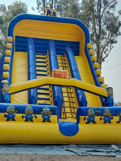 A full view of the Minions-themed inflatable slide. You can see the dual slides and the climbing nets in the center, all decorated with the funny Minion characters.