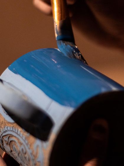 Applying a coat of blue underglaze before the carving begins. This is the first step in creating a vibrant sgraffito piece.