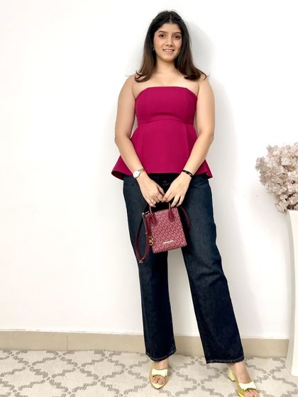 A fun and comfortable outfit featuring a magenta peplum tube top paired with dark wash straight-fit denims. The pop of color makes this a great look for a casual evening out.