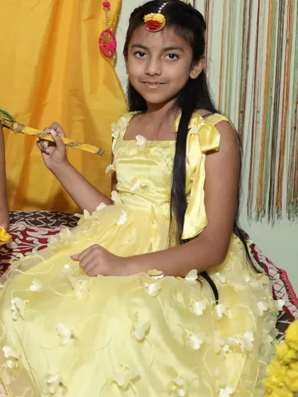 A close-up of a young girl in her yellow Haldi outfit, complete with a floral maang tikka. A perfect look for pre-wedding festivities.