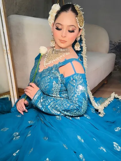 A full seated view of the teal blue lehenga, showing its beautiful color and design.