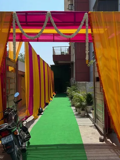 An entrance walkway created with colorful drapes and a green carpet, leading guests into the venue.