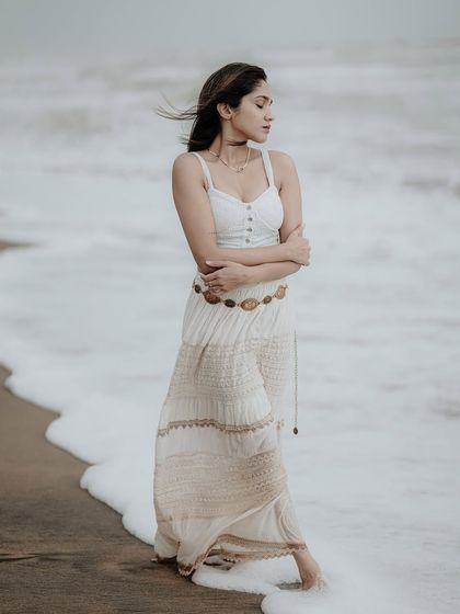 A serene portrait on the shoreline, with the waves gently washing over the sand. The soft, overcast light creates a calm and contemplative mood.