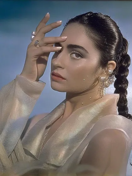 A close-up of Kavya Trehan, with her hand framing her face. The light catches the shimmer of her outfit, adding to the hyperreal and magical feel of the series.