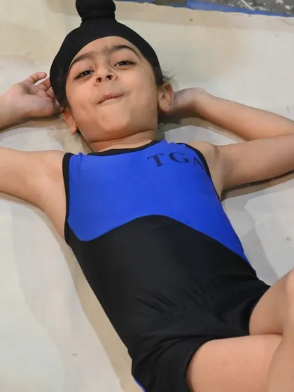A young gymnast relaxes on the mat. Even our champions need a moment to rest and recharge.