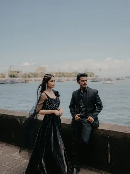 A stylish, posed shot of the couple by the sea wall. Their confident and relaxed postures give this photo a modern and fashionable feel.