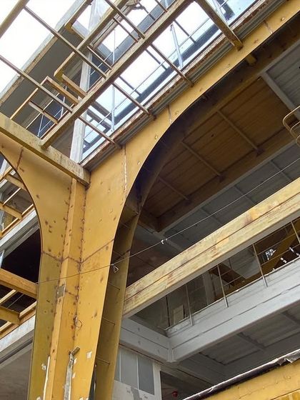 The original structure of the building, with its robust yellow steel frame, is exposed during the renovation. We chose to celebrate these industrial bones, integrating them into the new design as a nod to the building's past life.