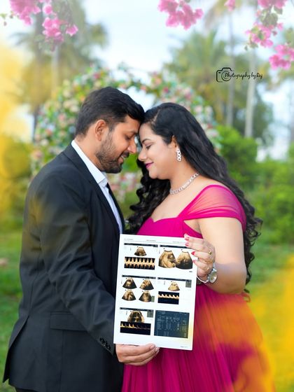 A sweet couple's portrait holding a sonogram, framed by a floral arch.