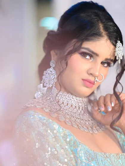 A close-up beauty shot of a model in a light blue lehenga, with a dreamy, ethereal effect. The focus is on the diamond jewelry and flawless makeup.