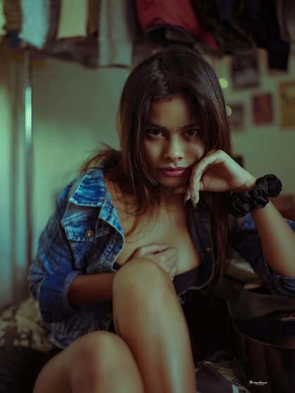 A moody and intense portrait with a strong, direct gaze. The dark tones and denim jacket give it a cool, rebellious vibe.