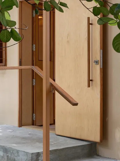 The entrance to the clinic is simple and welcoming, with a large wooden door and a gentle ramp providing easy access.