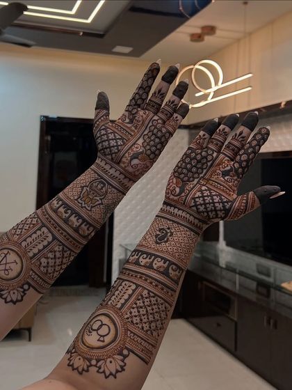 The full view of this intricate engagement mehendi, showing how the design looks in a home setting. The patterns are balanced and extend beautifully from the fingers to the elbows.