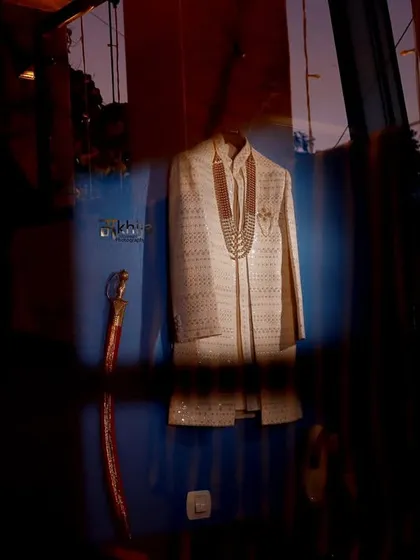 Another artistic shot of the groom's wedding attire. The play of light and reflections through the glass adds a layer of depth and creativity to this detail shot.