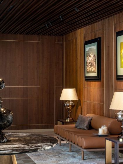 The entrance foyer sets a luxurious tone with rich wood paneling, brass inlays, and a striking modern sculpture. This area serves as a formal introduction to the home's elegant design language.