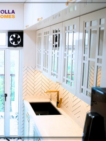 A shot of the vintage kitchen showcasing the custom white cabinets with glass inserts and the herringbone-patterned backsplash. The gold faucet adds a touch of modern luxury to the classic design.