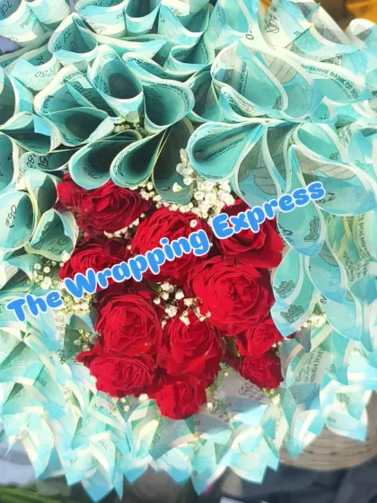A top-down view of the 5100 rupee note and flower bouquet. The currency notes create a beautiful border around the fresh red roses in the center.