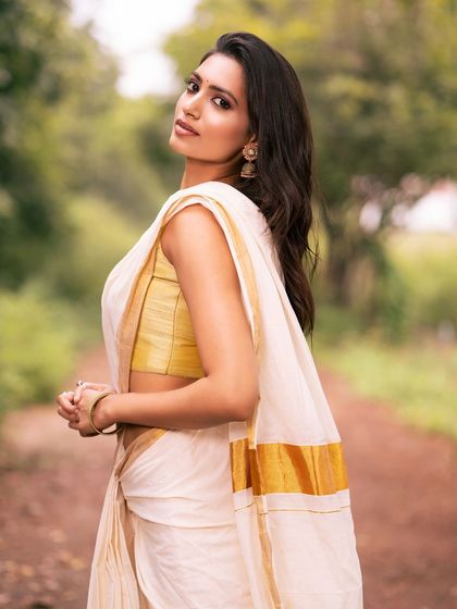 A classic portrait in a white and gold saree, with the model looking directly at the camera.