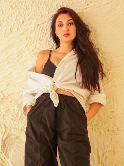 A confident, hands-in-pockets pose against a textured studio wall, creating a relaxed yet stylish portrait.