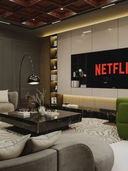 A modern entertainment room designed for relaxing and watching movies. The space features a large screen, comfortable curved sofas, and pops of green from the armchairs, all set against a sophisticated grey and wood palette.